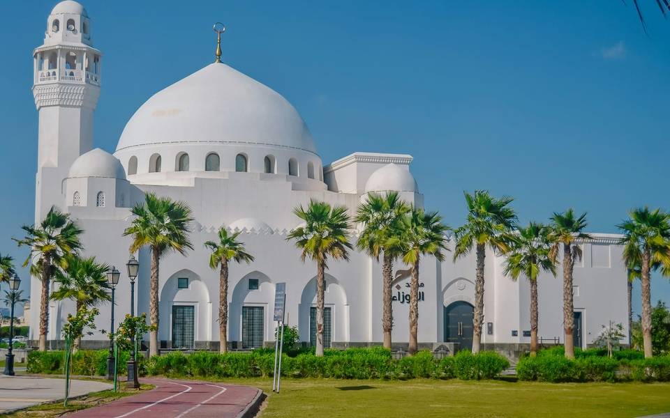 مسجد أبيض بقبة كبيرة تحيط به أشجار النخيل في المنطقة الشرقية