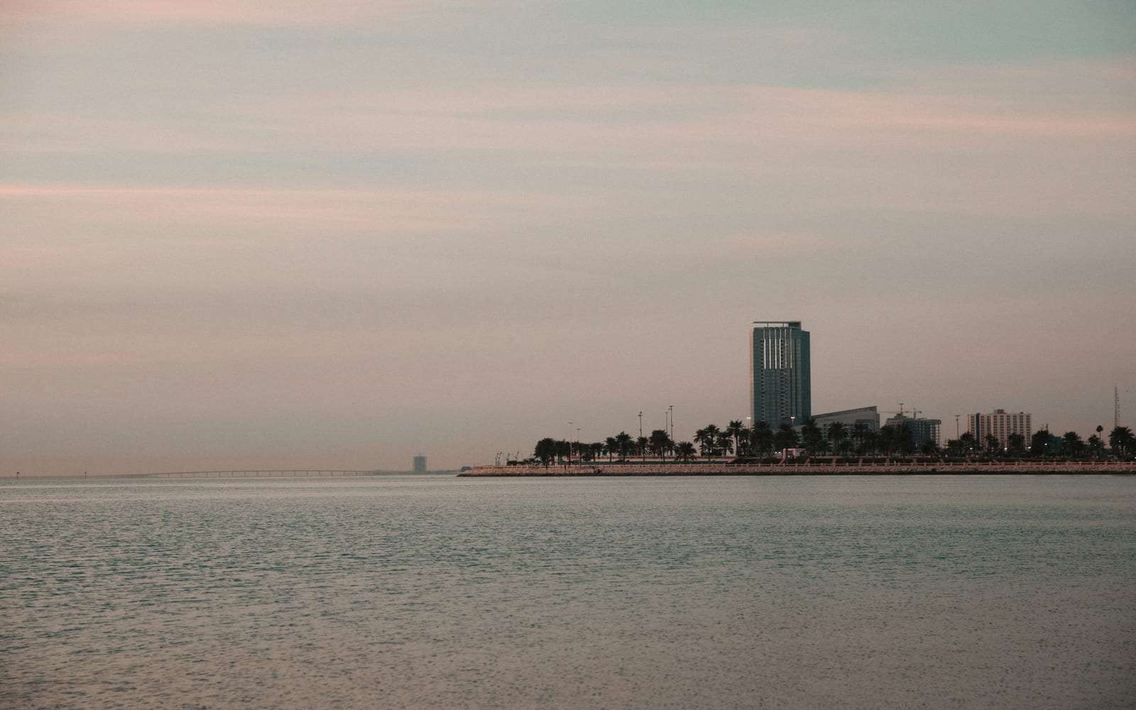 مياه الخليج الهادئة وأفق مدينة الخبر عند الغروب