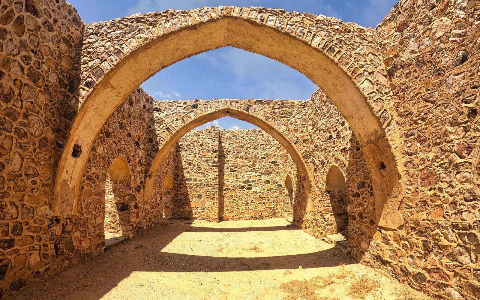 أقواس حجرية تاريخية تحت سماء زرقاء في الطائف